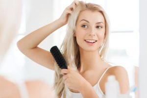 women in mirror looking at hair after hair restoration treatments