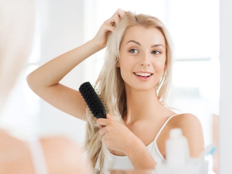 women in mirror looking at hair after hair restoration treatments